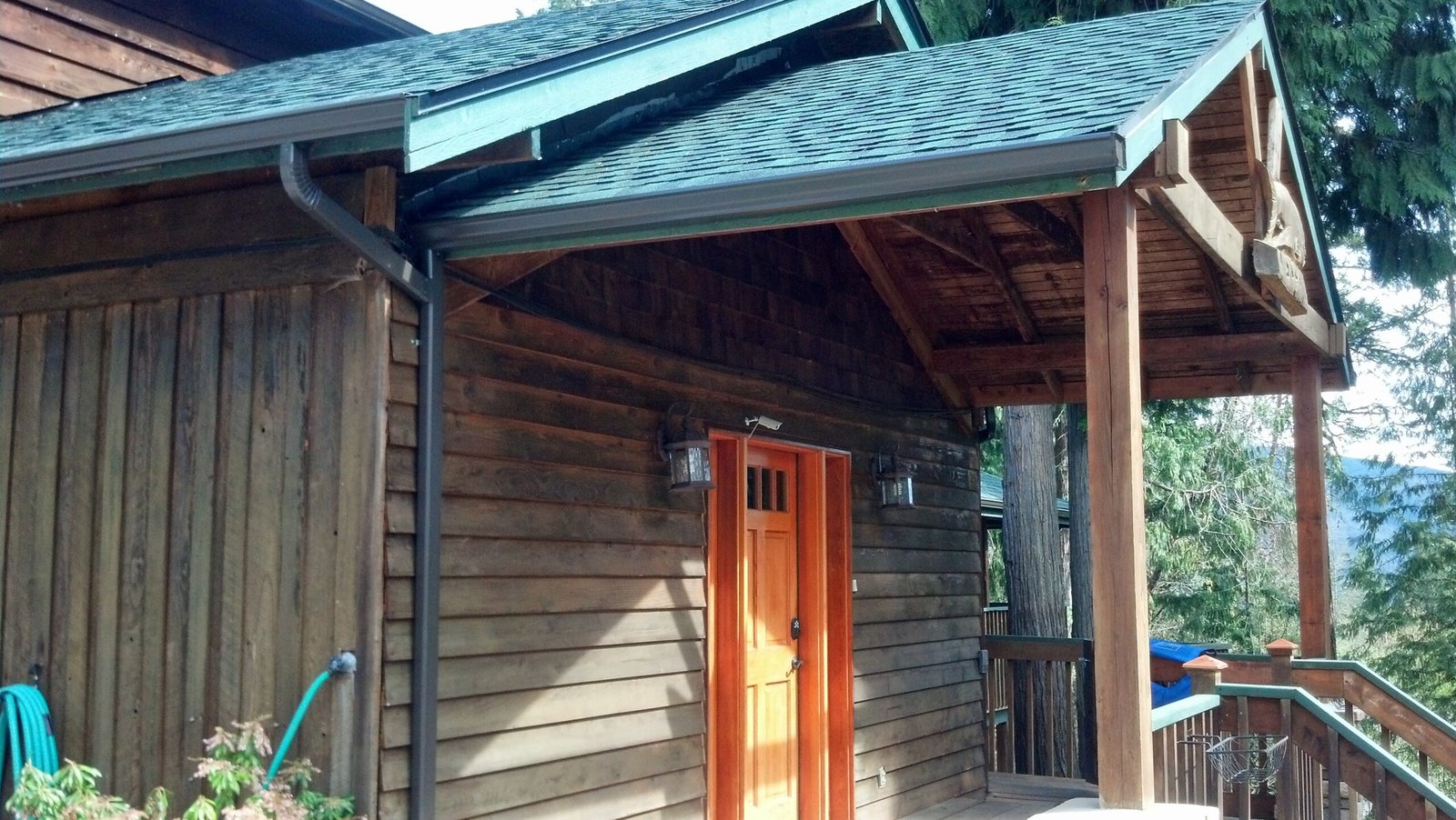 Gray gutters and downspout beside a timber-framed porch