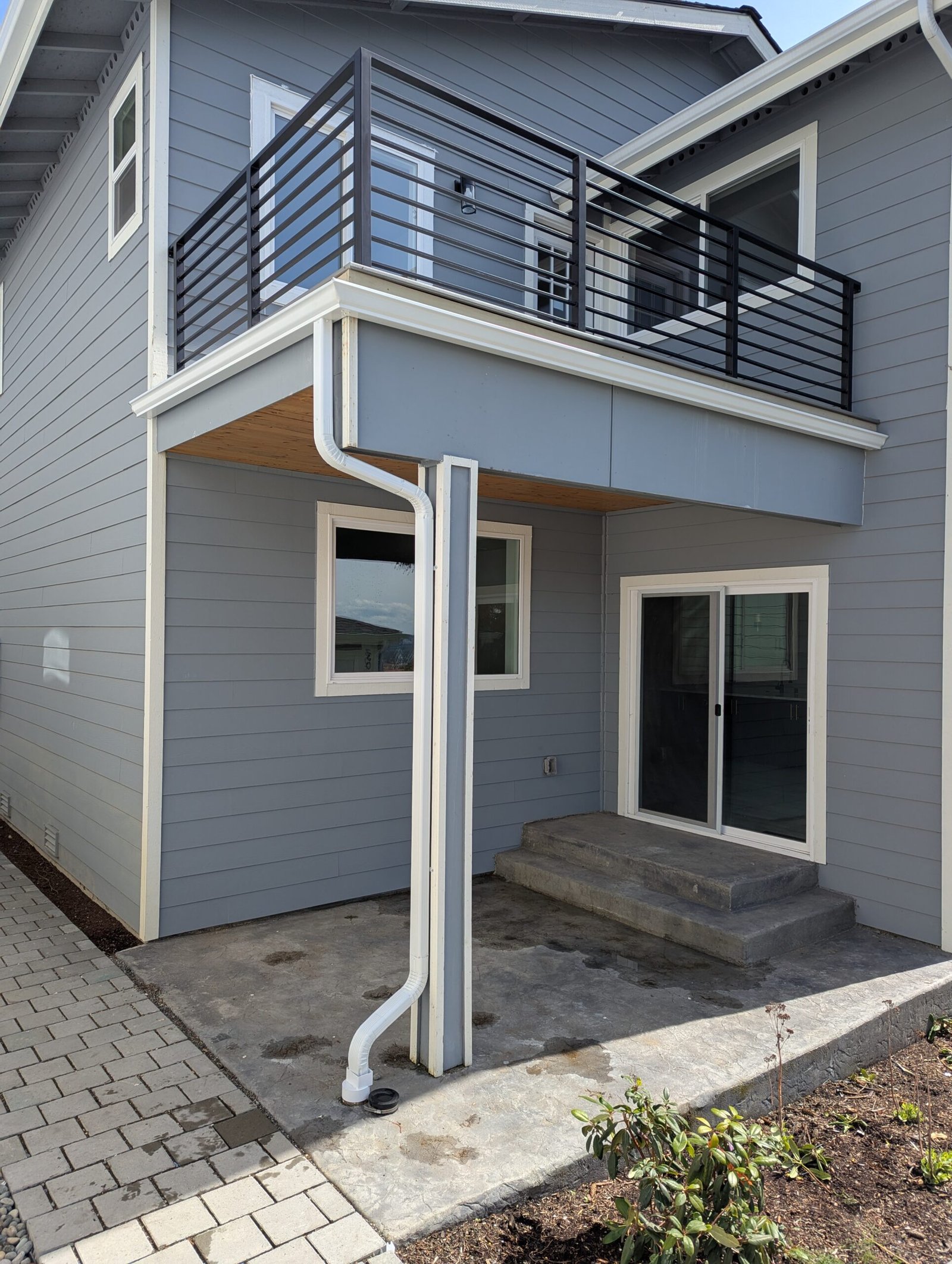 White balcony gutter and downspout routed along a support post